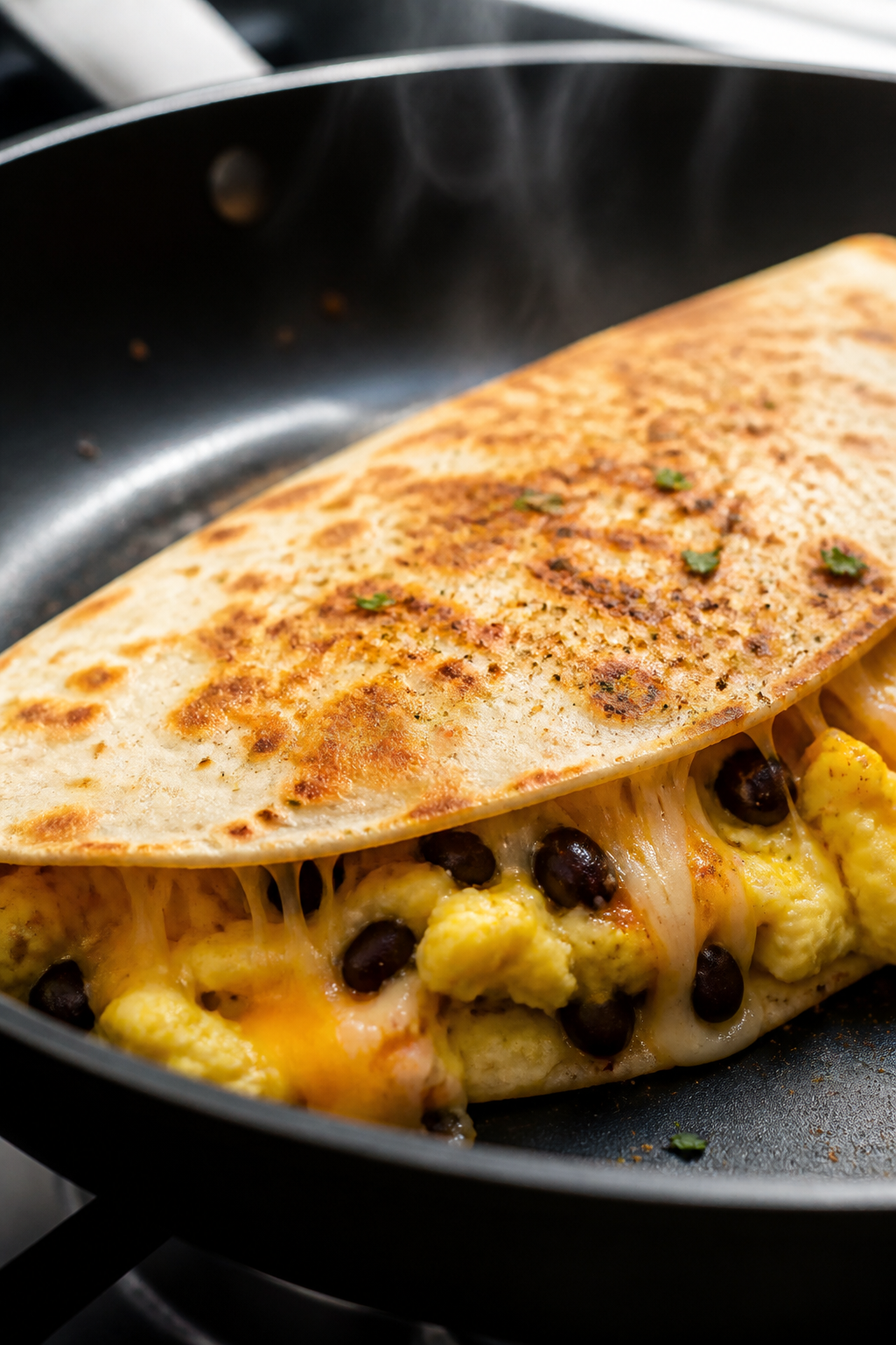 Close-up detail: A golden, folded breakfast quesadilla in a nonstick skillet mid-cook, cheese visibl